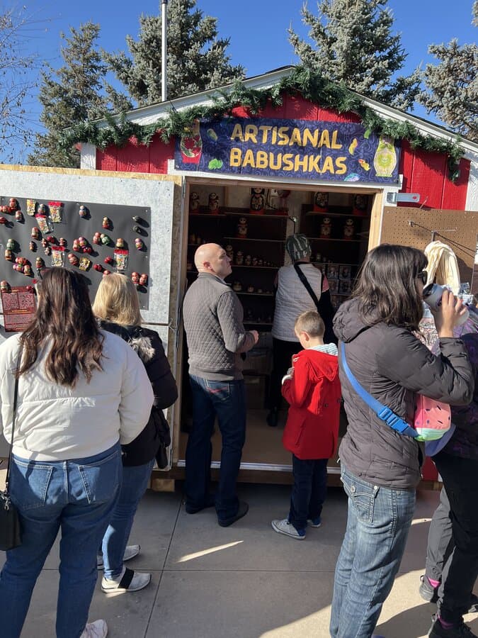 Visitors browsing the Artisanal Babushkas booth at Christkindlmarkt SLC during the day